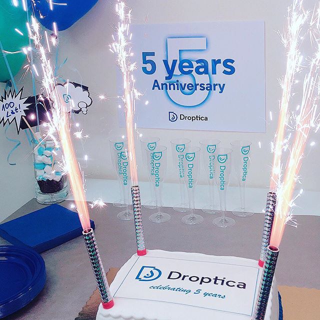 A birthday cake with sparklers. The sign above reads "The 5th anniversary of Droptica"