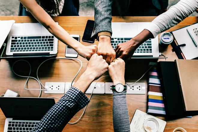 Five stretched hands over the desk doing fist bump in a gesture symbolysing good team and job done