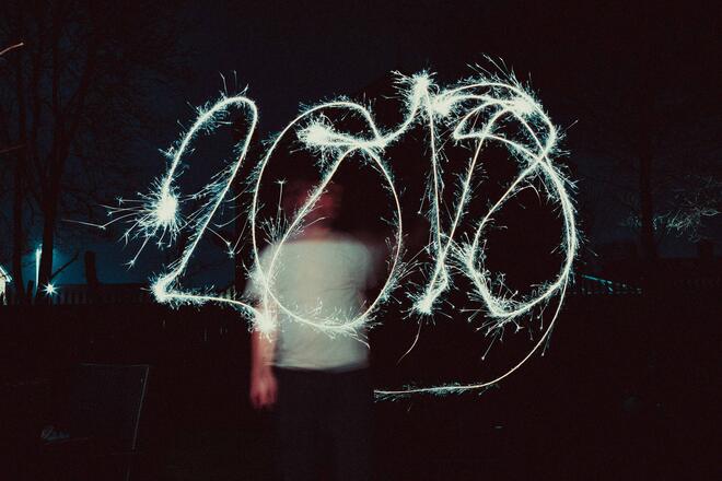 Fphoto made with long exposition. A man waves the sparkler to write "2018".