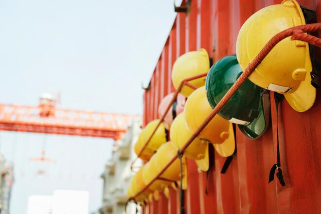Yellow and green hardhats for several teams of builders hanging from a contenair