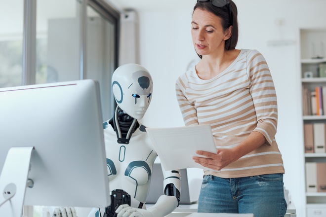Rédactrice de contenu relit des pages imprimées avec un robot humanoïde au bureau - métaphore de la collaboration humain-IA pour du contenu answer-first.