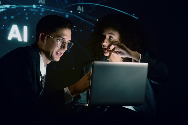 Deux professionnels examinent ensemble un ordinateur portable dans une pièce sombre éclairée par l'écran, avec des graphiques de réseau IA turquoise en arrière-plan – métaphore visuelle des décisions d'architecture Drupal multisite vs multilingue en équipe.