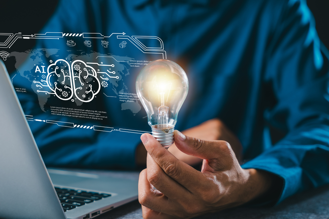 Personne devant un ordinateur portable tenant une ampoule lumineuse, avec un overlay holographique de cerveau IA - comment un contenu Drupal structuré aide les systèmes IA à lire et citer les pages web.