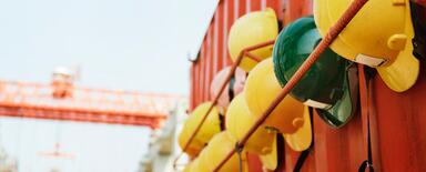 Yellow and green hardhats for several teams of builders hanging from a contenair