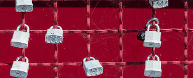 grey padlocks on the grey fence - symbol of security