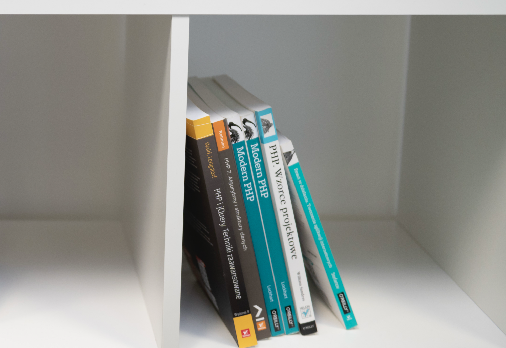 Collection of books about PHP and modern web development on a wooden shelf.